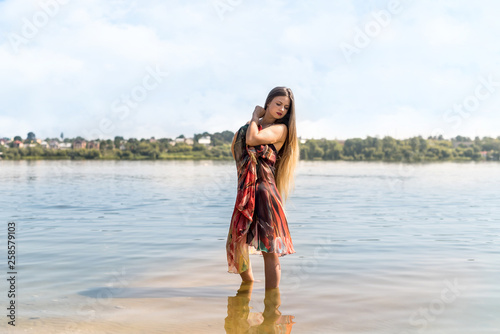 Woman in fashion dress posing on the ocean coast