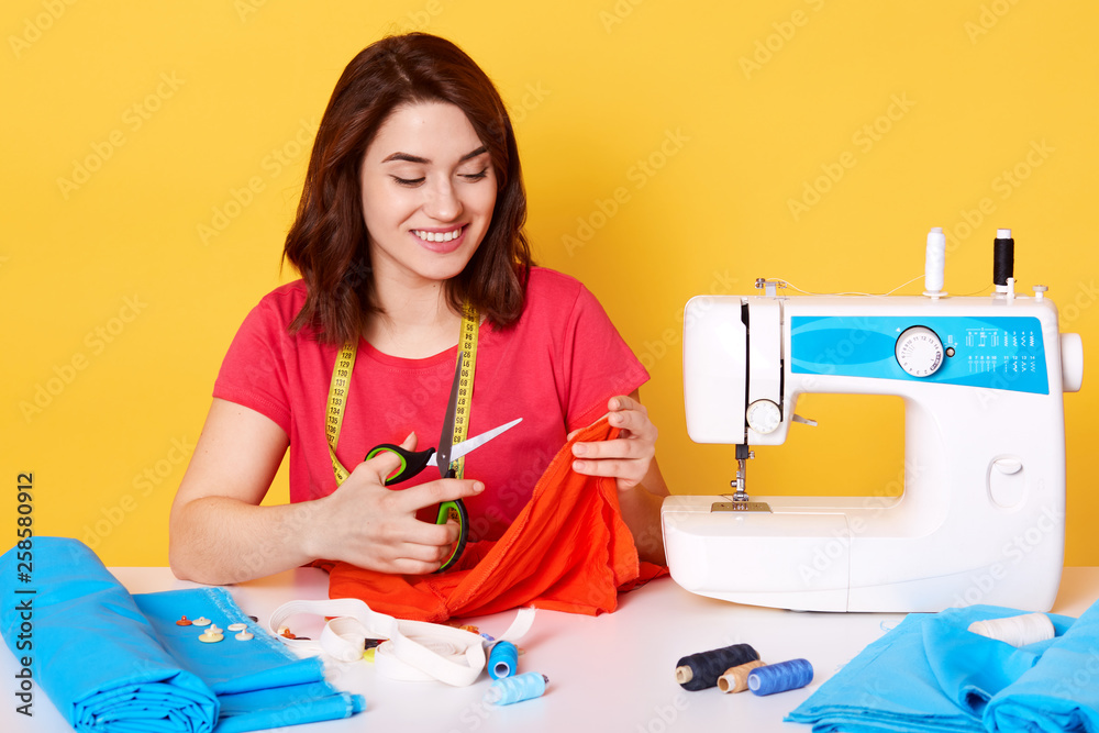 Premium Photo  Young dressmaker woman sews clothes on