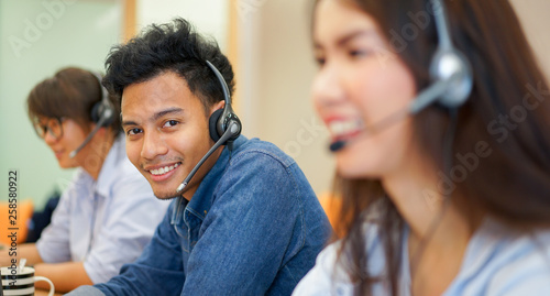 close up focus on asian call centre man with team working	