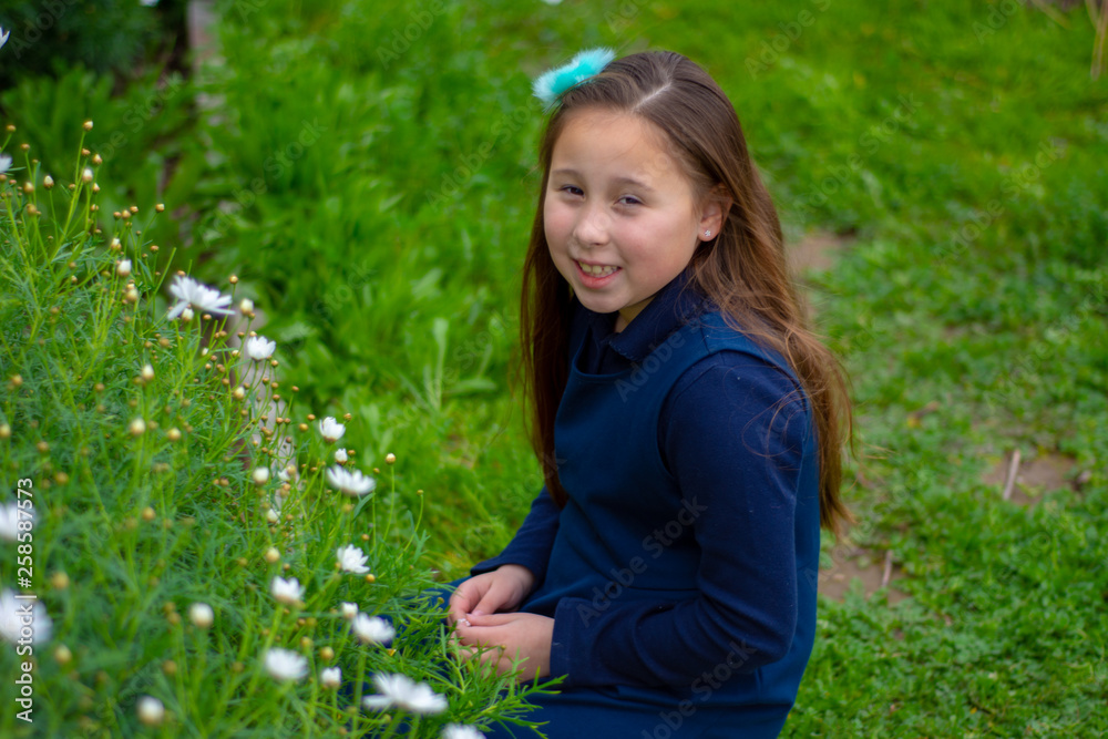 Smiling little latina girl in garden picking flowers Smiling little latina girl in garden picking flowers