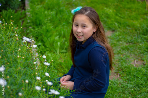 Smiling little latina girl in garden picking flowers