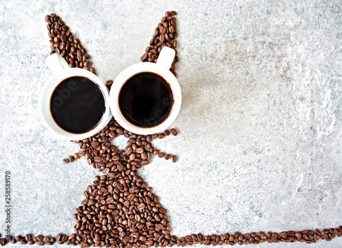 Canvas Print With fresh coffee beans and two cups of freshly brewed black coffee, a hare is s