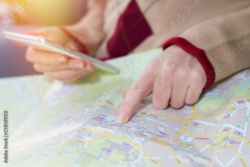hand with mobile phone pointing to the map, travel and vacation