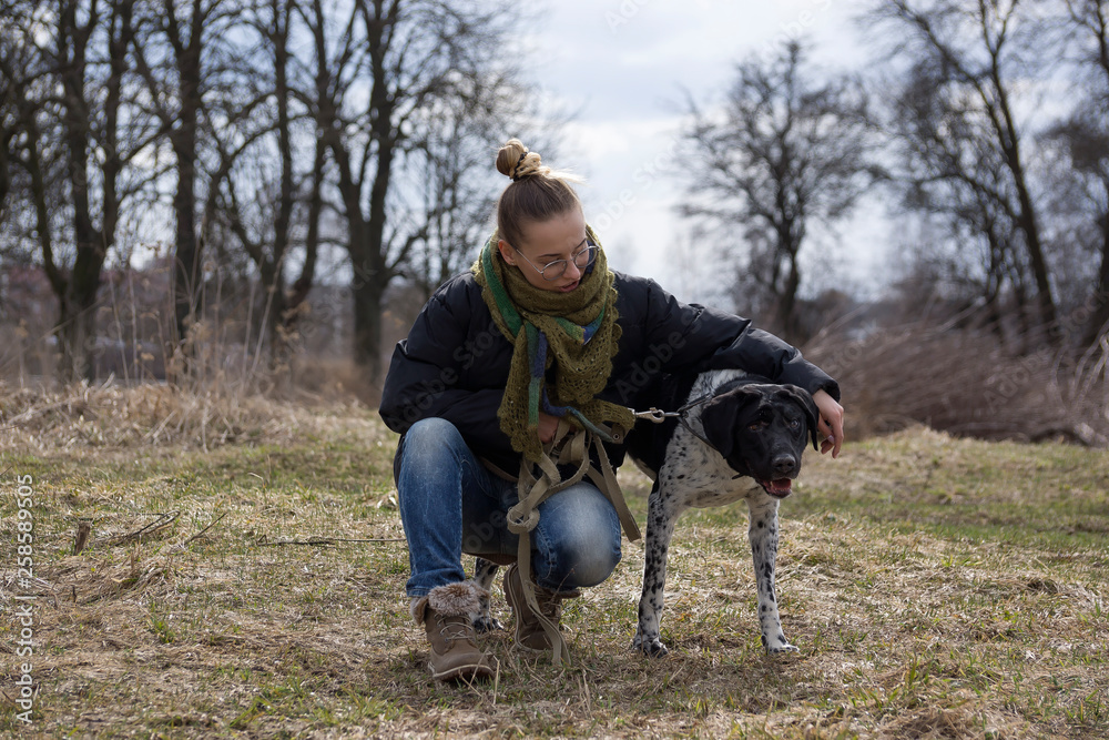 Young brunette girl with her dog walking in autumn park.