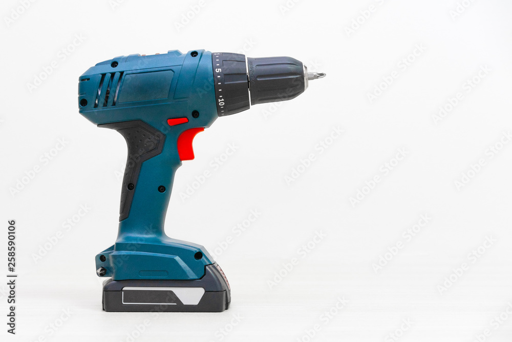 modern cordless screwdriver stands on the floor against a white wall. Not isolated modern cordless screwdriver stands on the floor against a white wall. Not isolated