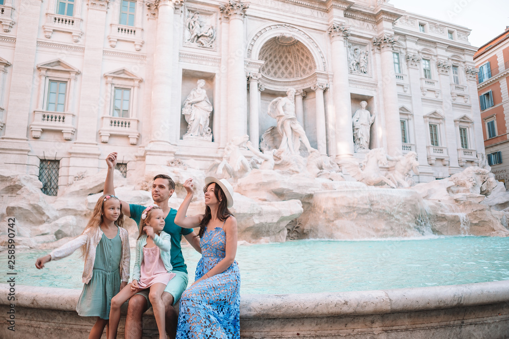 Happy family trowing coins at Trevi Fountain, Rome, for good luck. Little girls and parents making a wish to come back