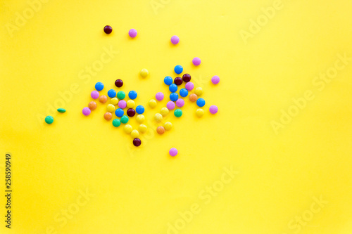 small colored candies, on a yellow background