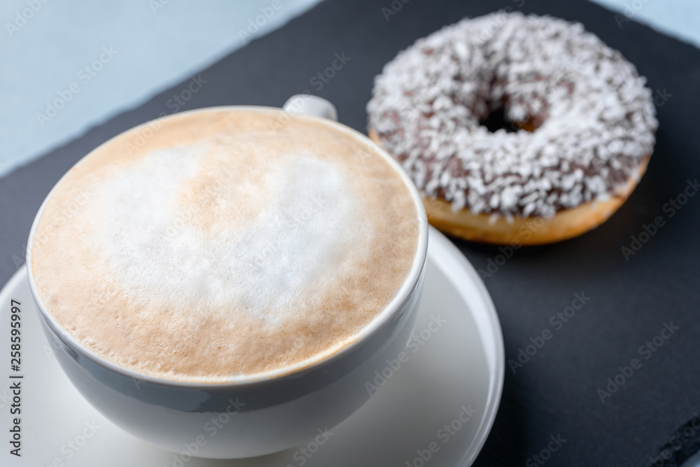 Cappuccino Cup on the background of a donut with coconut on a slate. Cappuccino Cup on the background of a donut with coconut on a slate.