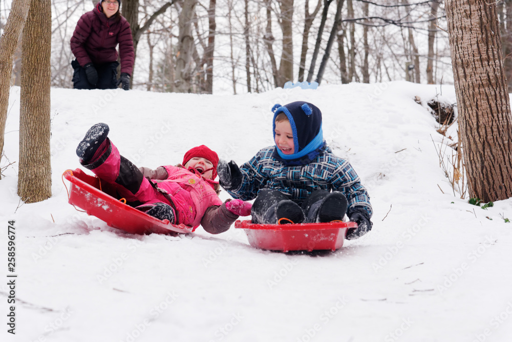 Brother and sisters (5 and 3 yrs old) sledging together in Quebec in winter Brother and sisters (5 and 3 yrs old) sledging together in Quebec in winter