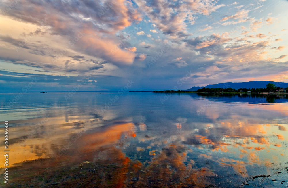 Obraz premium A dramatic sunset reflected in mirror calm waters of Maria, Baie des Chaleurs , Gaspesie in Quebec, Canada