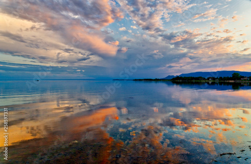 A dramatic sunset reflected in mirror calm waters of Maria, Baie des Chaleurs , Gaspesie in Quebec, Canada