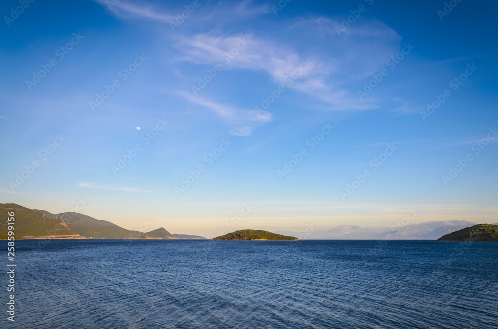 View of a very small uninhabited island with vibrant blue sea and sky View of a very small uninhabited island with vibrant blue sea and sky