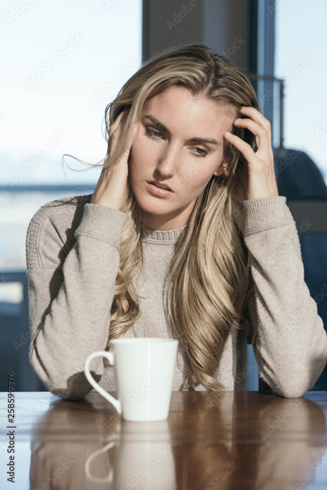 Grumpy blonde girl drinking hot liquid from white mug Grumpy blonde girl drinking hot liquid from white mug