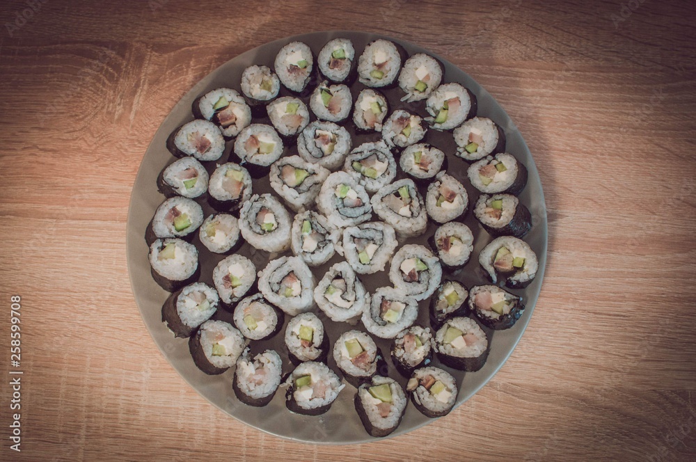 Plate of homemade sushi on wooden table. Plate of homemade sushi on wooden table.