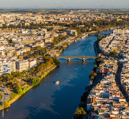 Aerial view of old downtown Sevilla at sunset showing Guadalquivir river, Puente de Triana, Plaza de Toros, Plaza de España, Triana, Torre del Oro, Calle Betis, Parks and other historical buildings. © Benur