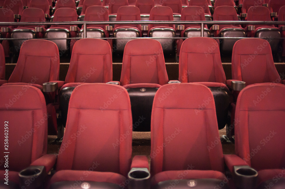Naklejka premium Empty cinema. Rows of comfortable red chairs towards to big screen in illuminate red room cinema. Mock Up.