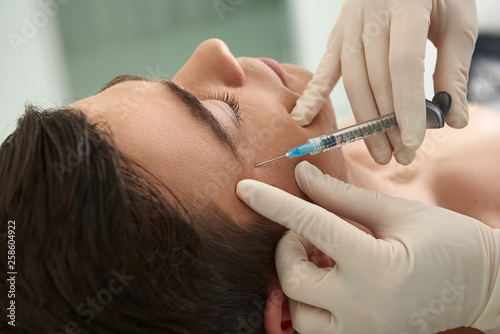 Obraz na płótnie Man on anti-wrinkling procedure of crows feet