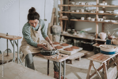 Photography Beautiful young lady in apron working in pottery workshop