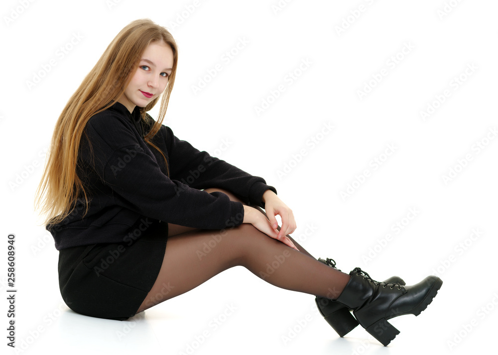 Fototapeta premium A teenage girl is sitting on the floor.