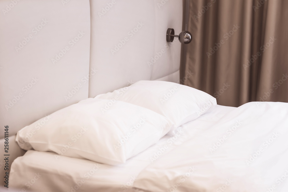 Bed in a bedroom with white linen, pillows and a blanket close up, sconces on the wall Bed in a bedroom with white linen, pillows and a blanket close up, sconces on the wall