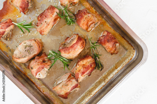 Roasted pork tenderloin wrapped in bacon and baked with white wine in a roasting pan.