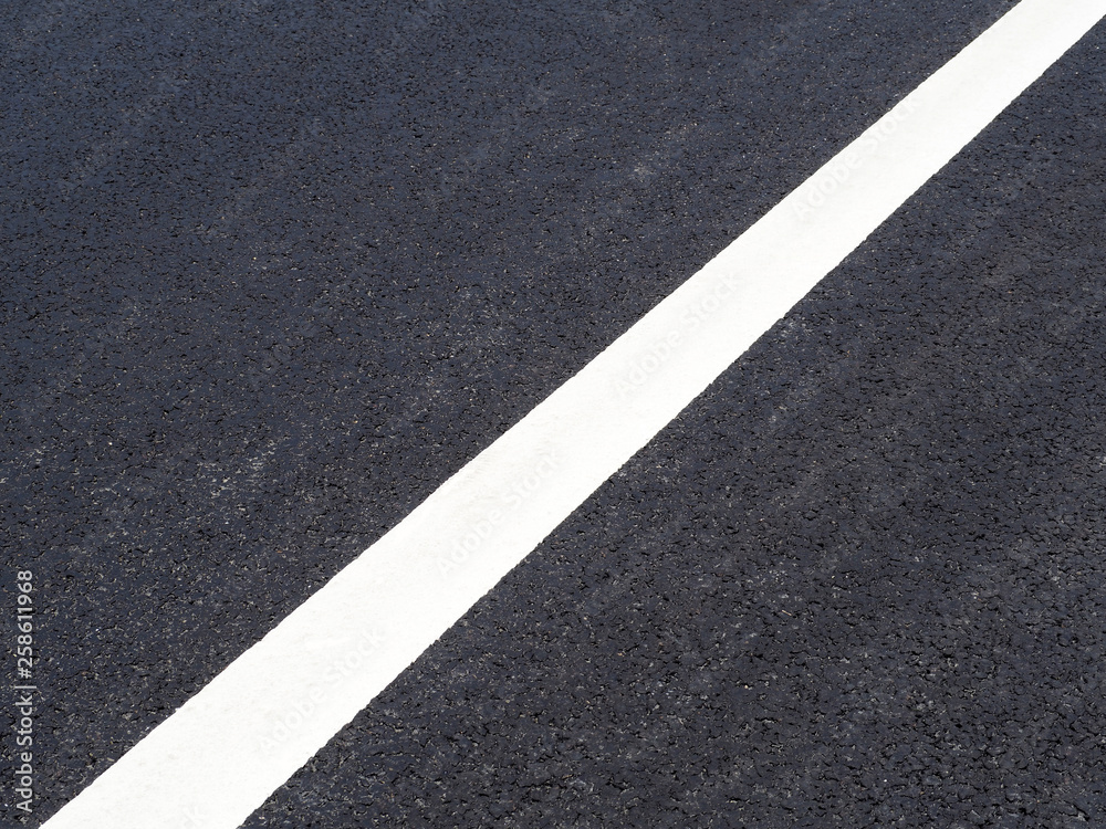 Road close up, black asphalt, white dividing strip diagonally
