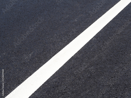 Road close up, black asphalt, white dividing strip diagonally © ANGHI