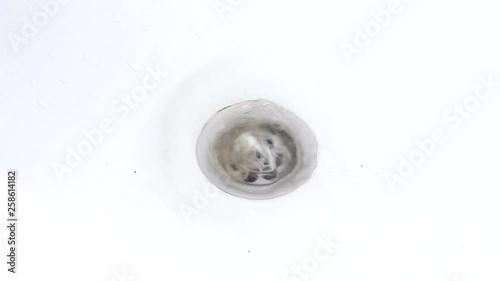 Water is drawn into the bath with hair in the drain hole of the bath, the water gurgles and rotates. Female hand pulls a bunch of hair from the drain hole
