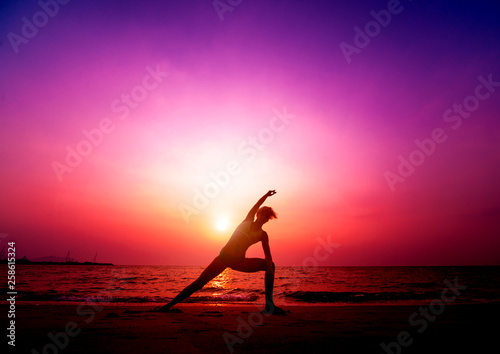 Beautiful young woman practic yoga at the beach. Early morning exercise. Sunrise © romaset