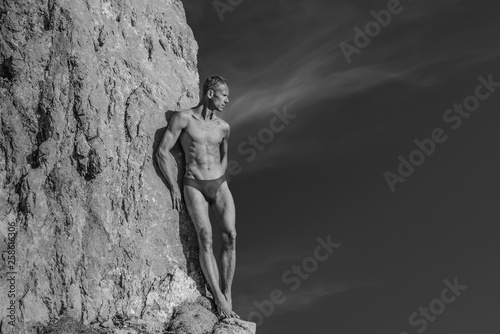 Nude  naked  man in the mountains near the rock  black and white. Natural wild strength and sexuality. Free space to insert text