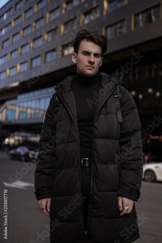 Portrait of young man near buildings on background. Street style.