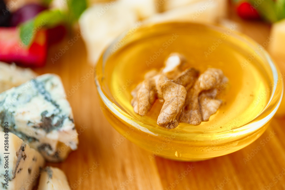 dorblu slices close up. Cheese plate served with fruits, walnuts and honey. delicious snack on wooden platter dorblu slices close up. Cheese plate served with fruits, walnuts and honey. delicious snack on wooden platter