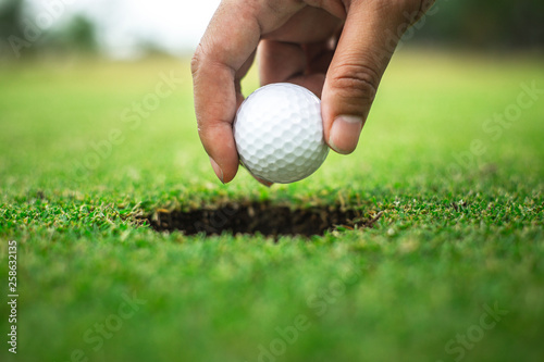 Hand of golfer holding golf ball form hole