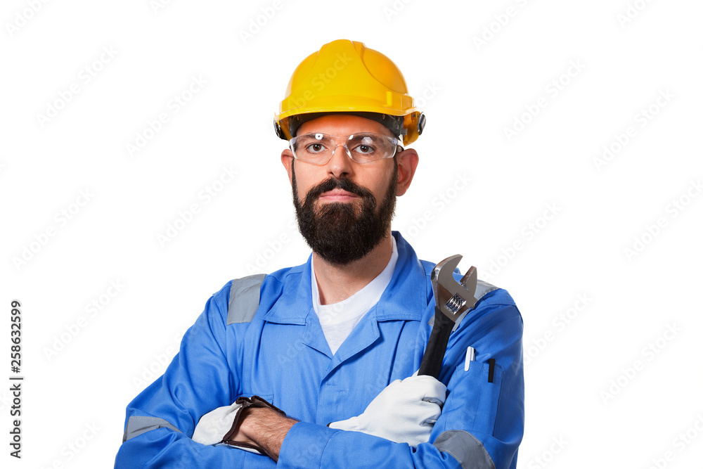Repair, construction, building, people and maintenance concept- man, a worker, in a yellow helmet and blue uniform holding a steel adjustable spanner over white background