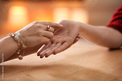 Chiromancer reading lines on woman's palm at table, closeup