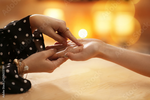 Fotografia Chiromancer reading lines on woman's palm at table, closeup