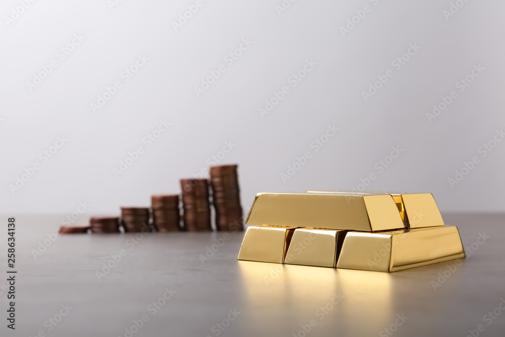 Obraz premium Stacked gold bars and coins on table. Space for text