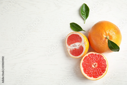 Fresh tasty grapefruits on white wooden background, top view with space for text