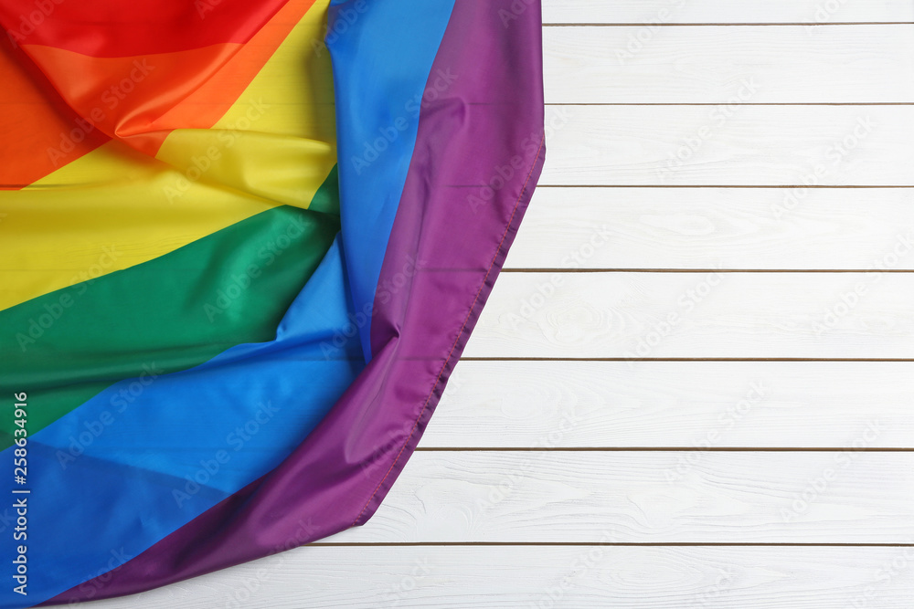 Bright rainbow gay flag on wooden background, top view with space for text. LGBT community