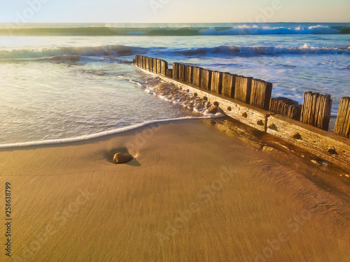 Wooden groin on beach to control erosion and sand movement  dawn or dusk.