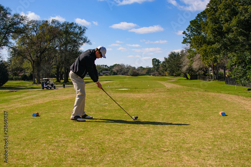 Golfer preparing to drive his tee shot with hit ball in frame on the tee box