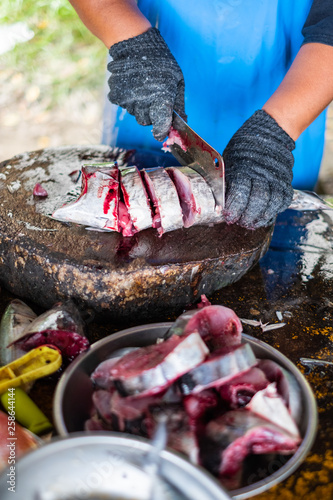 Fototapeta Naklejka Na Ścianę i Meble -  A fish seller uses sharp knife slicing fresh fish for customer
