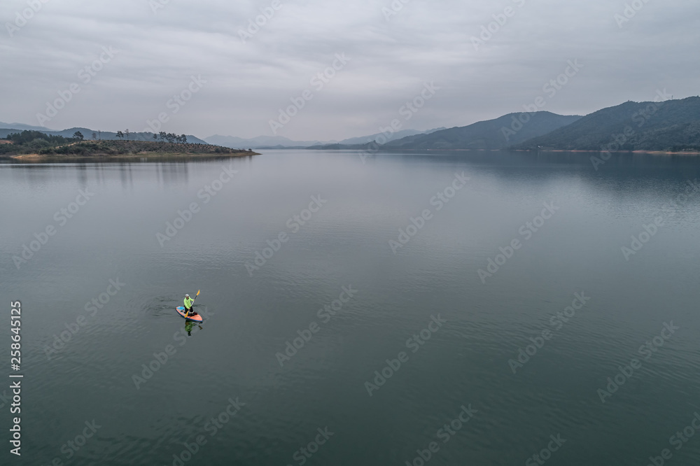 aerial view of a man stand up paddle boarding on the lake	