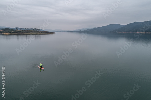 aerial view of a man stand up paddle boarding on the lake 