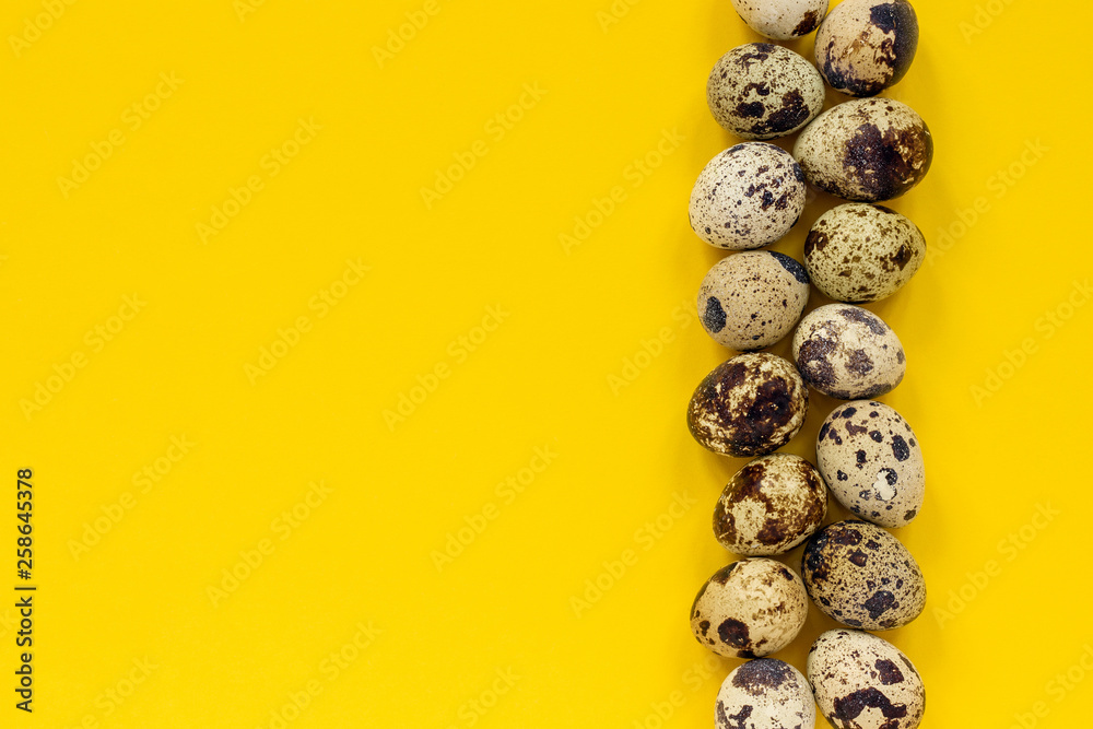 Row quail eggs on yellow paper background. Top view Copy space
