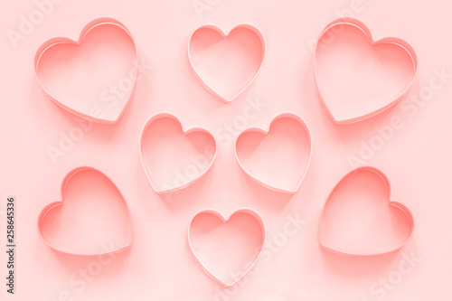 Pink cutters cookies in heart shape on pastel pink background, colar toned. Love romantic pattern, template