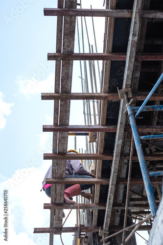 Construction worker welding metal rebar for the pouring cement of foundation.