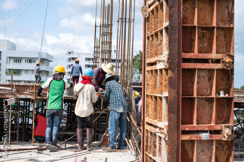 Workers collaborating in the installation of cement formwork frames at construction site.