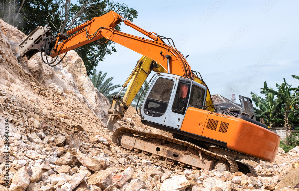 Large hydraulic Jackhammer working on smashing rock. Large hydraulic Jackhammer working on smashing rock.