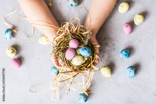 Photography Children's hands holding colorful easter eggs which lying in nest